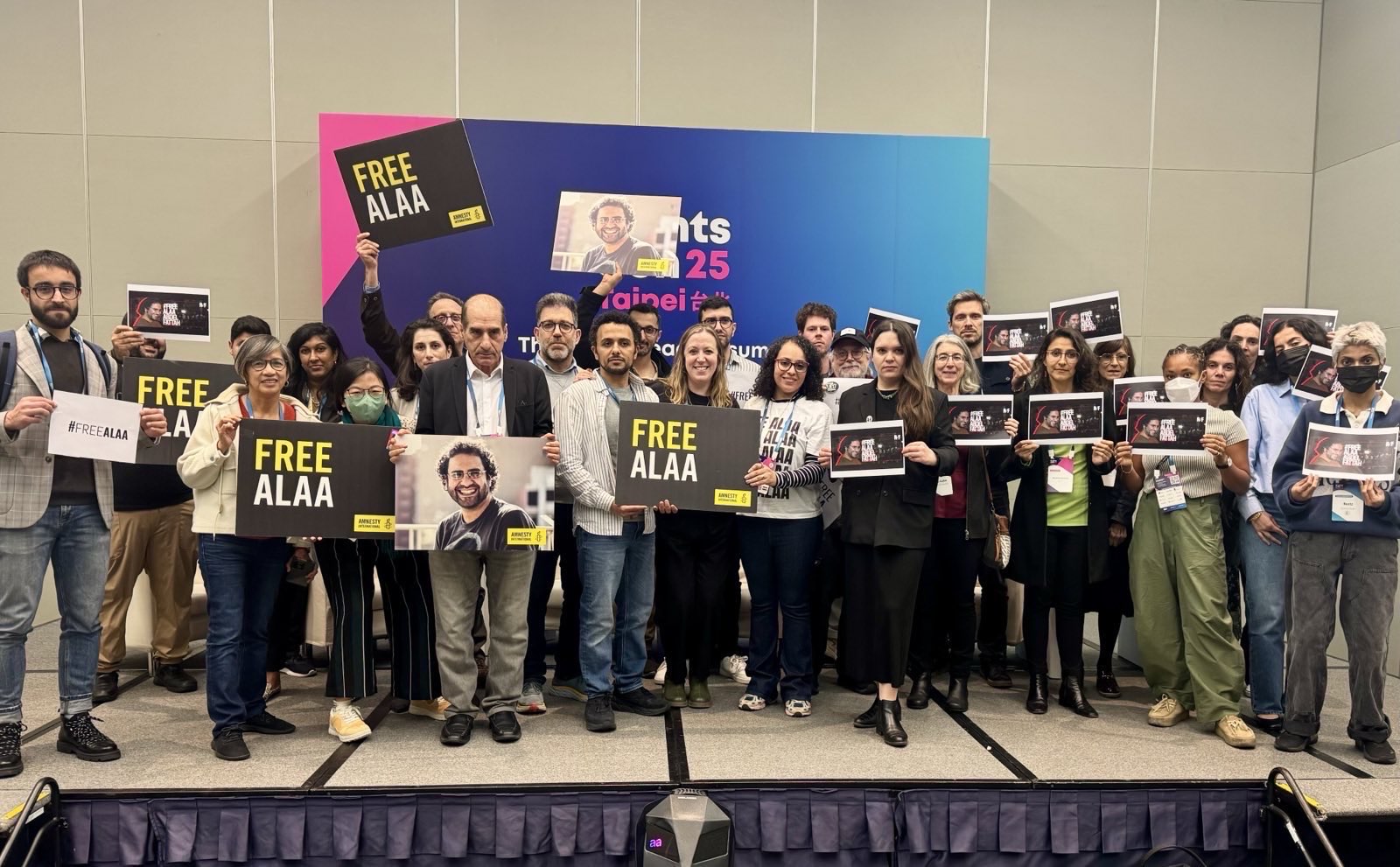 a group of people at RightsCon in Taipei holding signs for Alaa Abd El Fattah to be freed