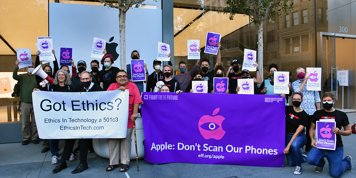 25 people holding banners in front of an apple store