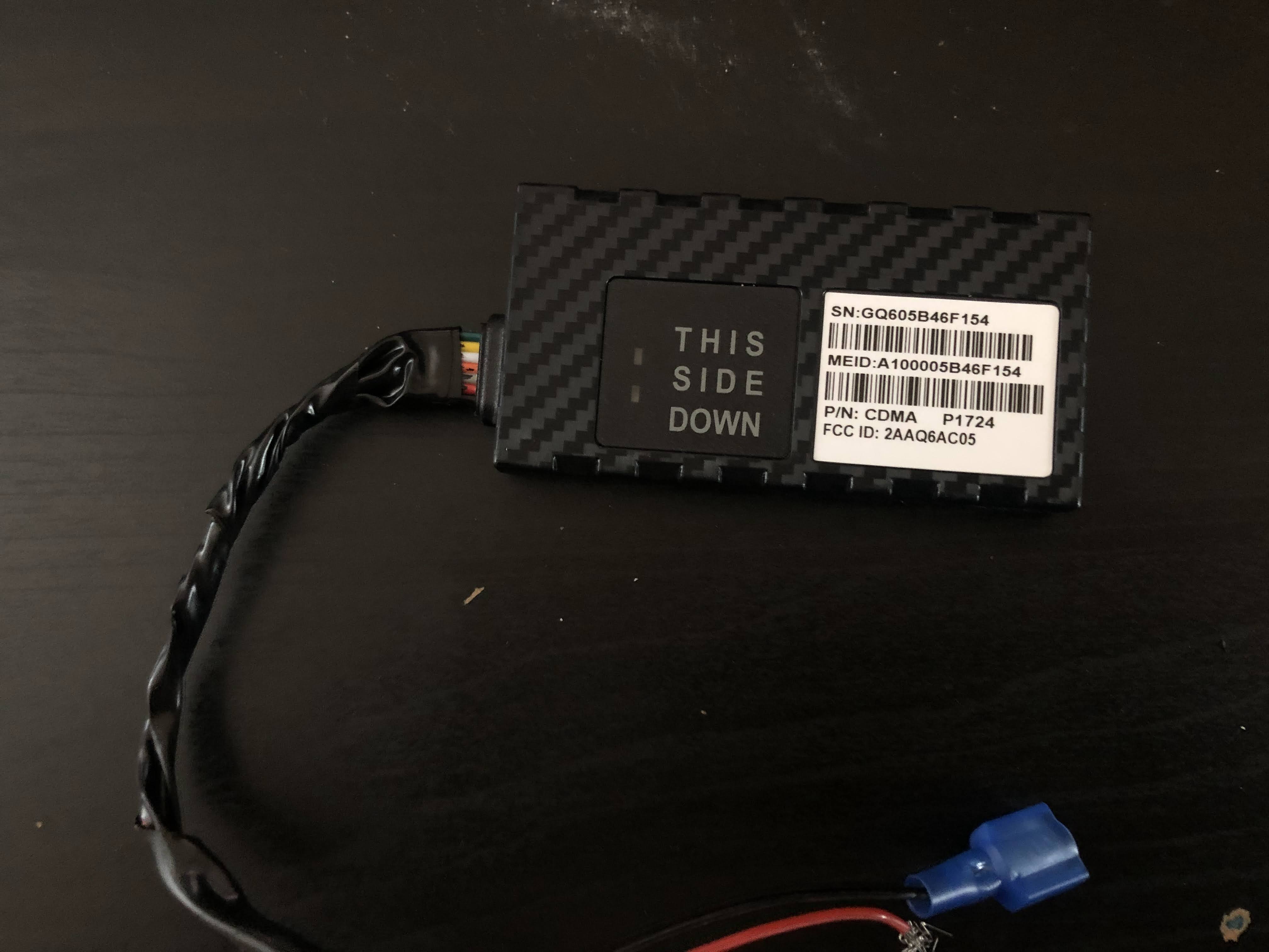 A GPS tracker found in a car. The front reads "this side up." There are three barcodes and wires coming out of the end.