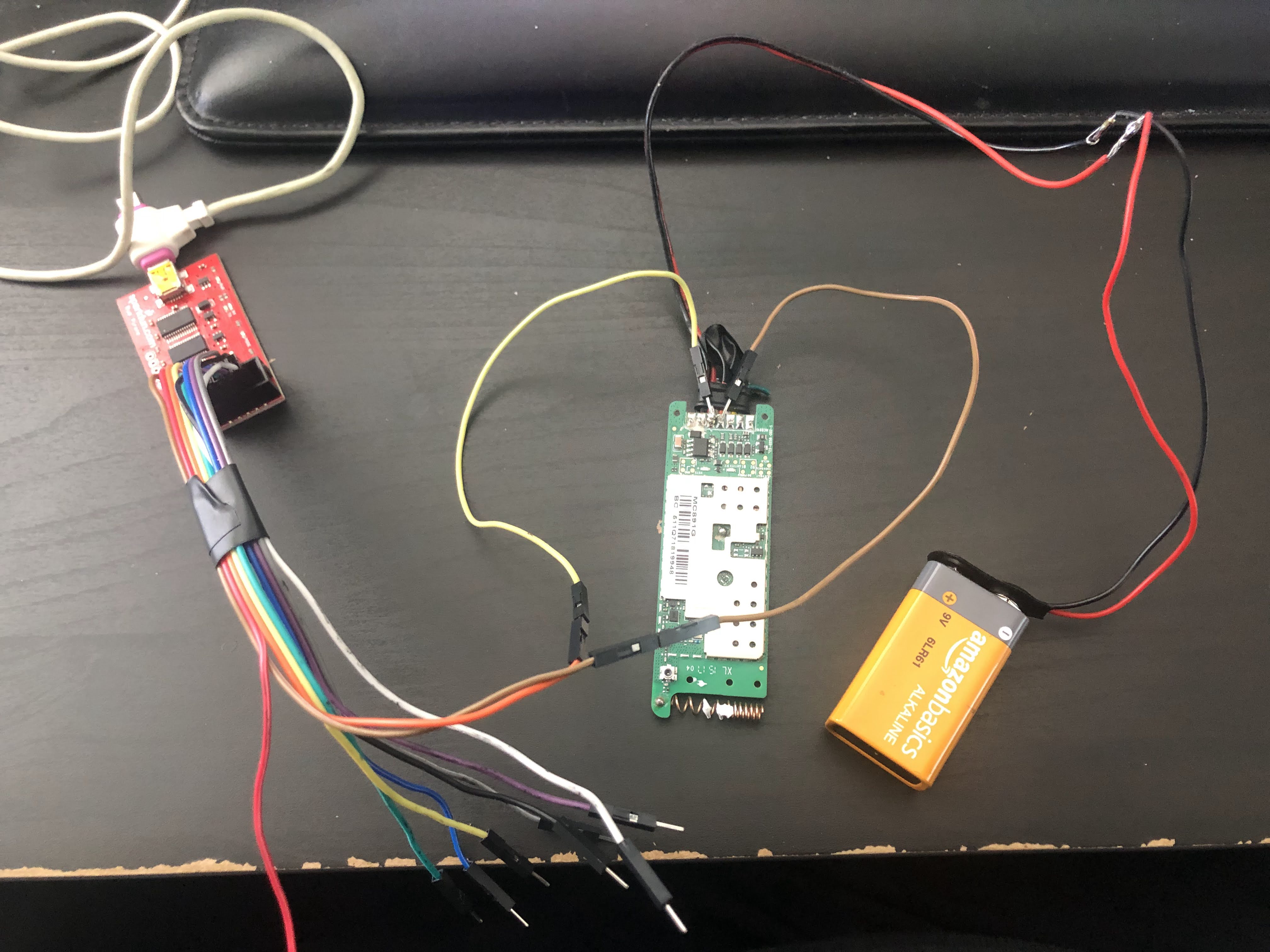 The Bus pirate connected to wires soldered to the GPS tracker. The GPS Tracker is also connected to a 9 volt battery.