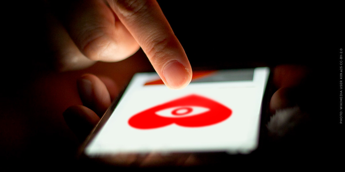 A person scrolls on a phone, viewing a spying heart