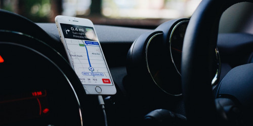 image of an iphone mounted on a car dashboard, with a map application on the screen